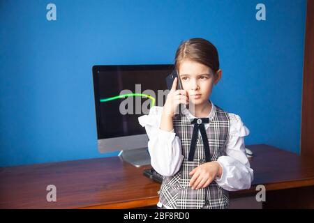 a girl in a business suit stands at the computer and talks on the phone Stock Photo