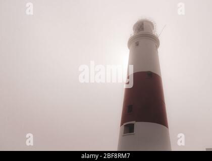 Portland Bill lighthouse on a foggy summer morning as the sun tries to break through behind, Portland, Dorset, UK Stock Photo
