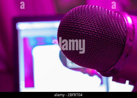 Pro microphone for broadcast with laptop on background in purple light. Podcast studio with copy space Stock Photo