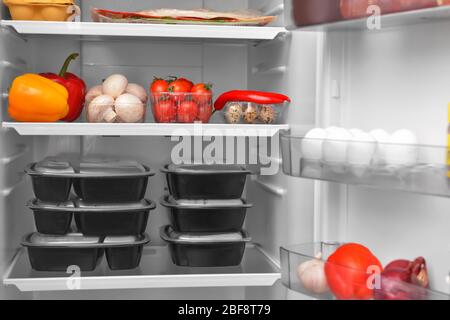 Containers with healthy food on shelf in fridge Stock Photo