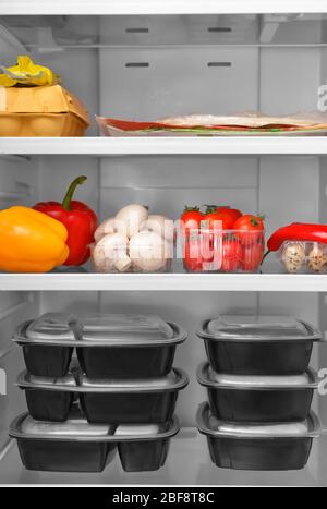 Containers with healthy food on shelf in fridge Stock Photo