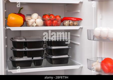 Containers with healthy food on shelf in fridge Stock Photo