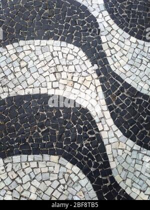 Sidewalk of Copacabana Beach, Brazil. Promenade of Rio de Janeiro. Background, urban texture. Real pattern made with small black and white stones. Stock Photo