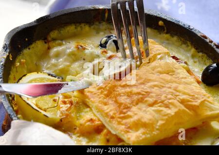 Salmon cake on a pan with sauce lemon and black olives. Stock Photo