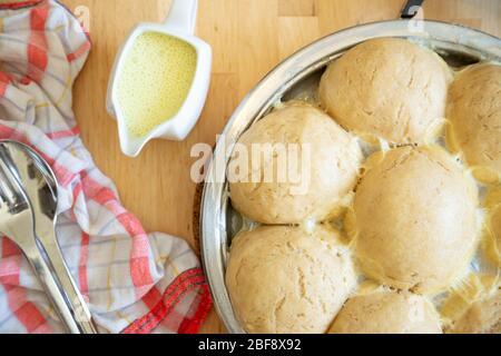 Traditional fresh bavarian yeast dumplings, vegan version, served with vanilla sauce in a pan Stock Photo