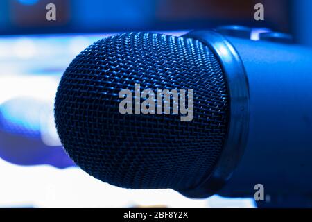 Concept of podcast or broadcasting radio. Pro condenser mic with blurry background with laptop. Blue light Stock Photo