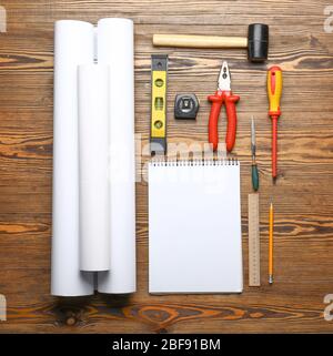 Blueprints with builder's tools and notebook on wooden background Stock Photo