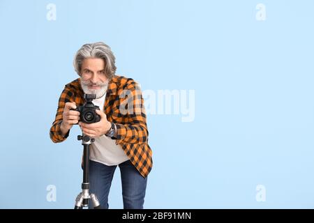 Handsome senior photographer on color background Stock Photo