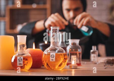 Flasks with potion and candles on table in alchemist's laboratory Stock Photo