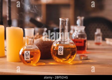 Flasks with potion and candles on table in alchemist's laboratory Stock Photo