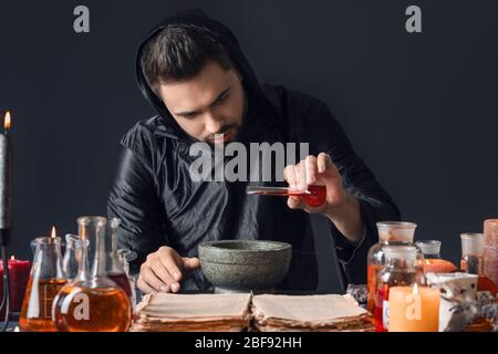 Male alchemist making potion on dark background Stock Photo