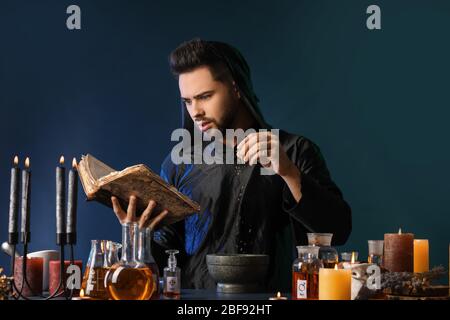 Male alchemist making potion on dark background Stock Photo