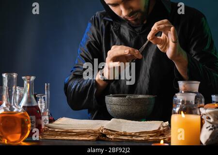 Male alchemist making potion on dark background Stock Photo