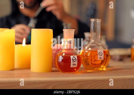 Flasks with potion and candles on table in alchemist's laboratory Stock Photo