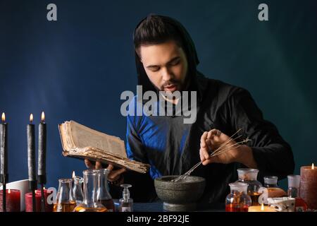 Male alchemist making potion on dark background Stock Photo