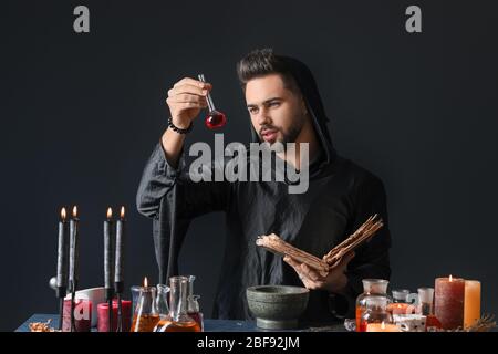 Male alchemist making potion on dark background Stock Photo
