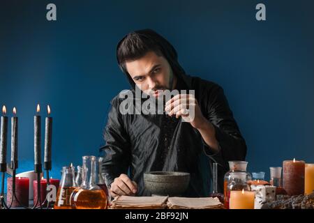 Male alchemist making potion on dark background Stock Photo