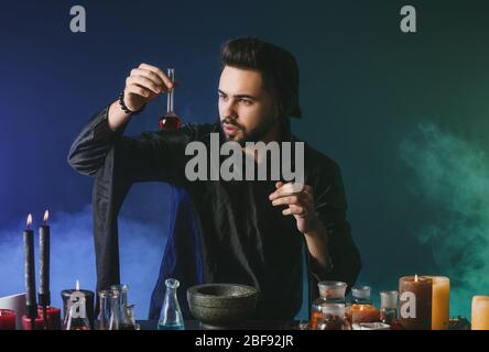 Male alchemist making potion on dark background Stock Photo