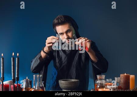 Male alchemist making potion on dark background Stock Photo