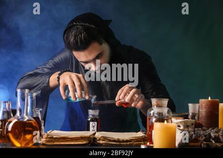 Male alchemist making potion on dark background Stock Photo