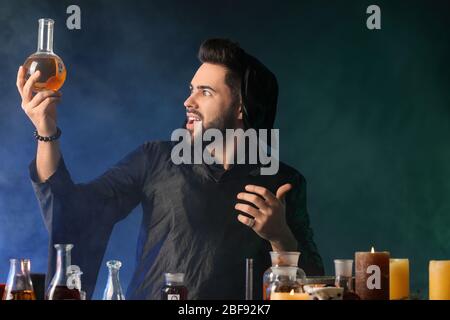Male alchemist making potion on dark background Stock Photo