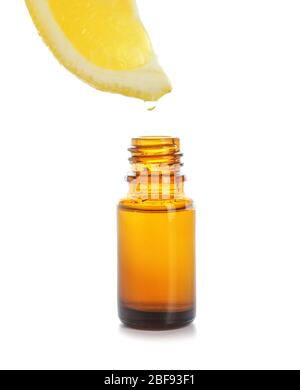 Essential oil dripping from lemon slice into bottle on white background Stock Photo