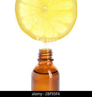 Essential oil dripping from lemon slice into bottle on white background Stock Photo