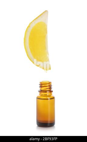 Essential oil dripping from lemon slice into bottle on white background Stock Photo