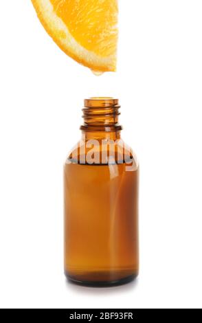 Essential oil dripping from orange slice into bottle on white background Stock Photo