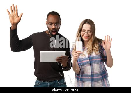 Young man and woman using laptop, devices, gadgets isolated on white studio background. Concept of modern technologies, tech, emotions, ad. Copyspace. Shopping, gaming, meeting online education. Stock Photo
