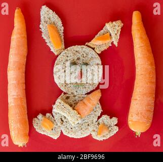 Beautiful bunny made with wholemeal sandwich bread, capers, carrots and goji berry on a red background Stock Photo