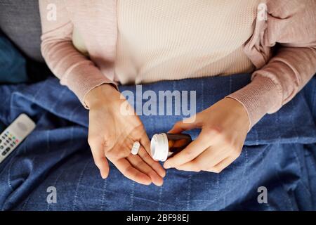 Close-up of woman taking vitamins out of the bottle for illness Stock Photo