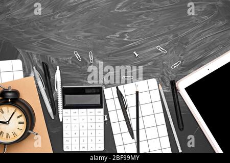 School supplies with alarm clock and tablet computer on dark background Stock Photo