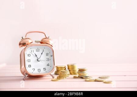 Alarm clock and coins on wooden table. Time management concept Stock Photo