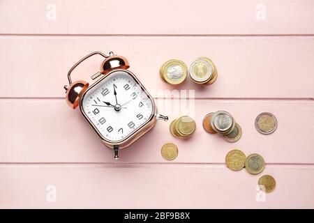 Alarm clock and coins on wooden table. Time management concept Stock Photo