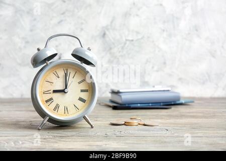 Alarm clock and coins on wooden table. Time management concept Stock Photo