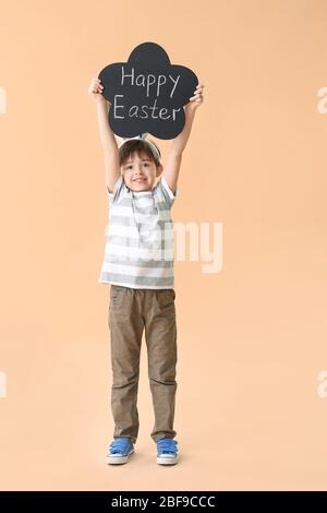 Little boy holding chalkboard with text HAPPY EASTER on color background Stock Photo