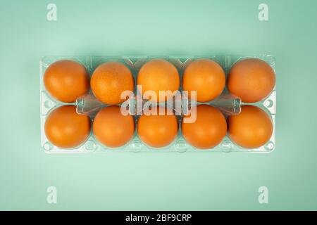 Overhead view of brown chicken eggs in an open egg box isolated on green. Fresh chicken eggs background. Top view with copy space. Natural healthy foo Stock Photo