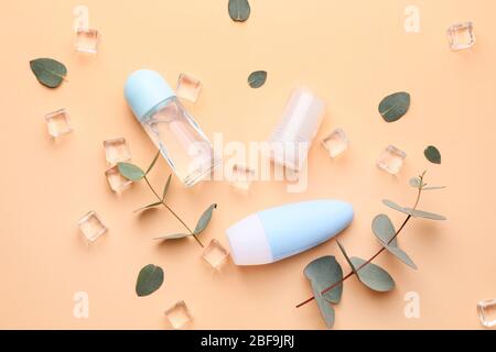 Different deodorants, ice cubes and eucalyptus on color background Stock Photo