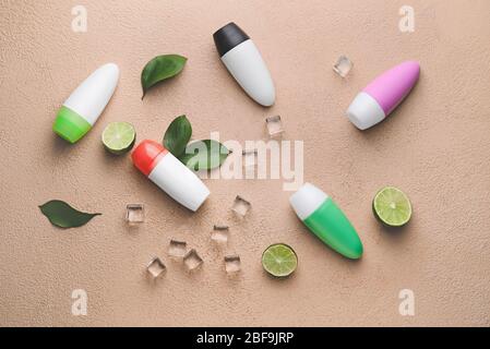 Different deodorants, lime and ice cubes on color background Stock Photo