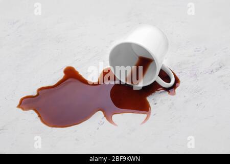 Overturned cup and spilled coffee on table Stock Photo