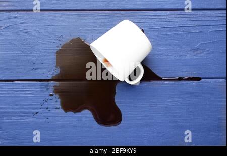 Overturned cup and spilled coffee on table Stock Photo