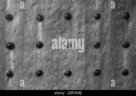 Closeup of grunge black metal plate with rivets and screws as background or texture Stock Photo