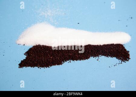 brown coffee grinds with white sugar granules against a blue background Stock Photo