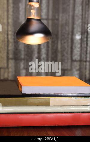 Pile of paperback books and novels on a table and under the study light. Stock Photo