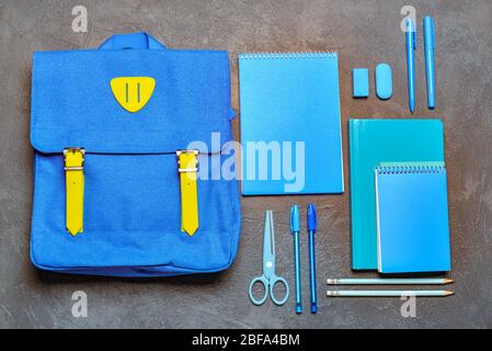 School backpack and stationery on grey background Stock Photo