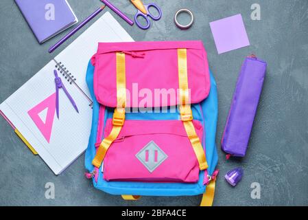 School backpack and stationery on grey background Stock Photo