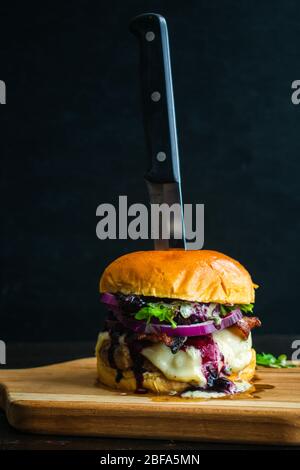 Red, White, and Blueberry Bacon Burger with Basil Aioli: Bacon cheeseburger topped with Havarti cheese, blueberry compote, red onion, arugula, and bas Stock Photo
