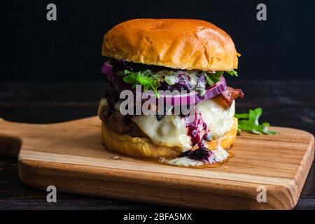 Red, White, and Blueberry Bacon Burger with Basil Aioli: Bacon cheeseburger topped with Havarti cheese, blueberry compote, red onion, & arugula Stock Photo