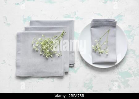 Napkins, plate and floral decor on light background Stock Photo